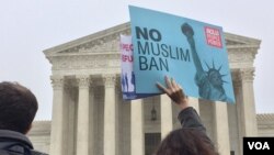 2018年4月25日，华盛顿的美国最高法院外，一名示威者举着反对旅行禁令的标语。