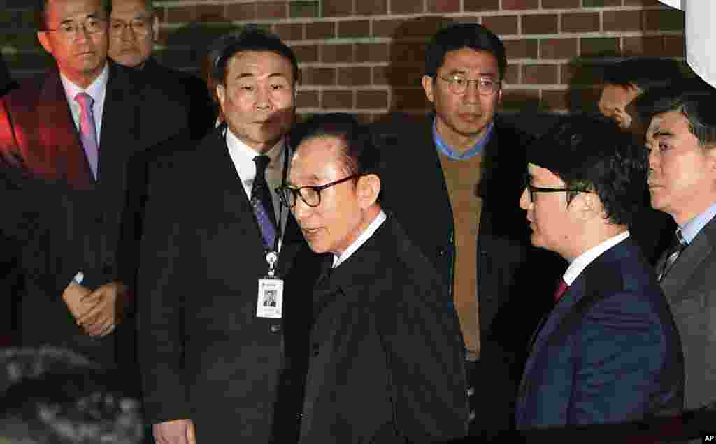 Former South Korean President Lee Myung-bak, center, gets into a car at his residence in Seoul as he is transferred to a detention center. A South Korea court issued an arrest warrant for ex-president on corruption charges.