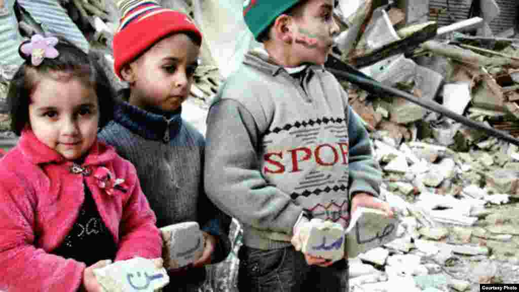 Trẻ em Syria cầm các viên gạch từ một tòa nhà bị dội bom ở thành phố Homs, ngày 10/1/2013.