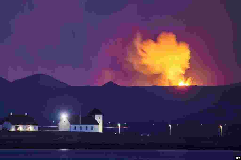 Bessastadir, the official residence of the President of Iceland is seen with the glow from the lava coming out of a fissure near the Fagradalsfjall on the Reykjanes Peninsula behind.
