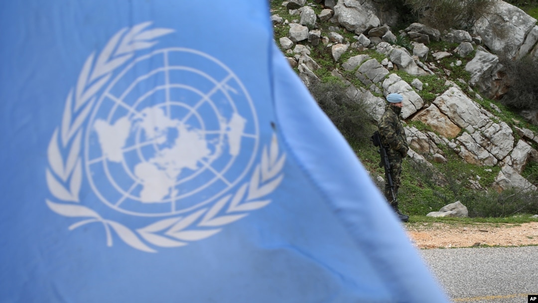 FILE - A United Nations peacekeeper is seen standing on patrol behind a U.N. flag.