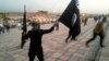 FILE - An Islamic State fighter holds the extremist group's signature flag and a weapon in the Iraqi city Mosul, June 23, 2014. Preparations are underway to wrest the city from IS control.