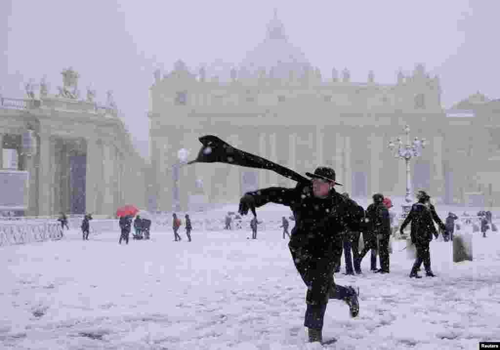 A young priest throws a snow ball during a heavy snowfall in Saint Peter's Square at the Vatican, Italy.