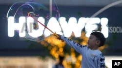 一名儿童在北京华为标识附近玩泡泡（2019年5月20日）。
