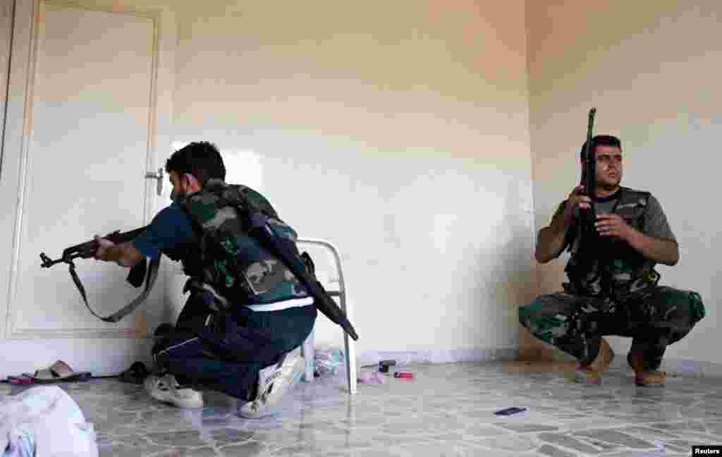 Thành viên của Quân đội Syria Tự do, núp trong một căn nhà, trong trận giao tranh với quân đội chính phủ trong quận Saif al-Dawla của Aleppo, 22/8/12