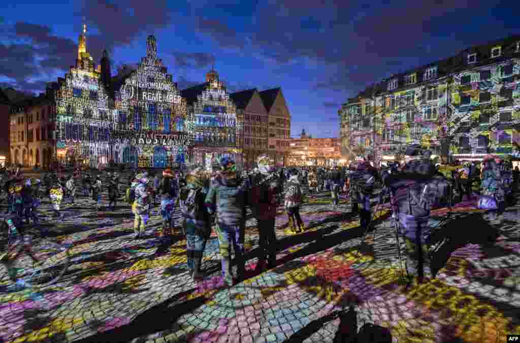 Visitors watch the light installation "Frankfurt Fades" by artist Philipp Geist presented during the Luminale Festival of Light at the Roemer square in Frankfurt am Main, western Germany, March 20, 2018.