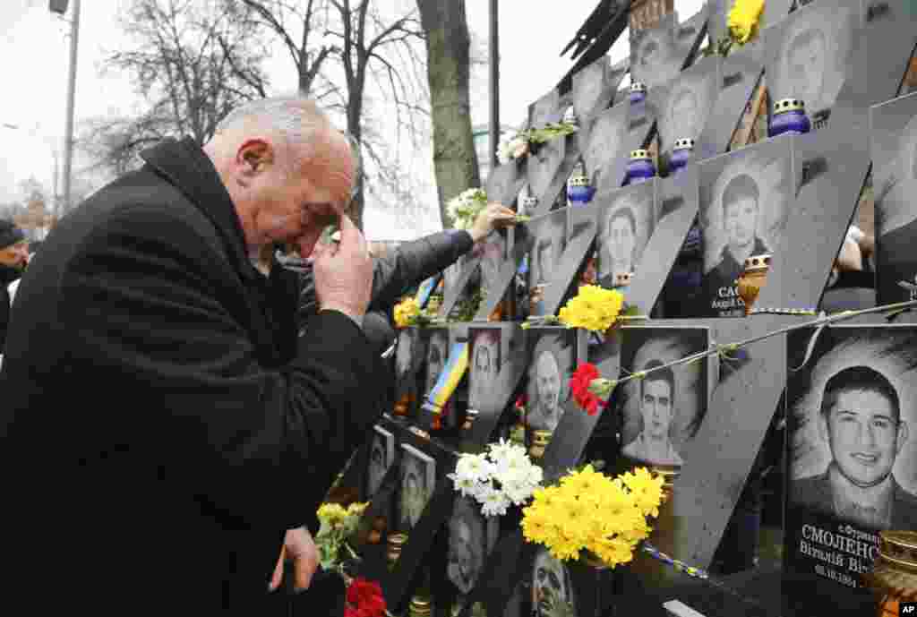 A man pays his respect at a memorial dedicated to people who died in clashes with security forces, at the Independent Square (Maidan) in Kyiv, Ukraine, to mark the fourth anniversary of the start of the protests.