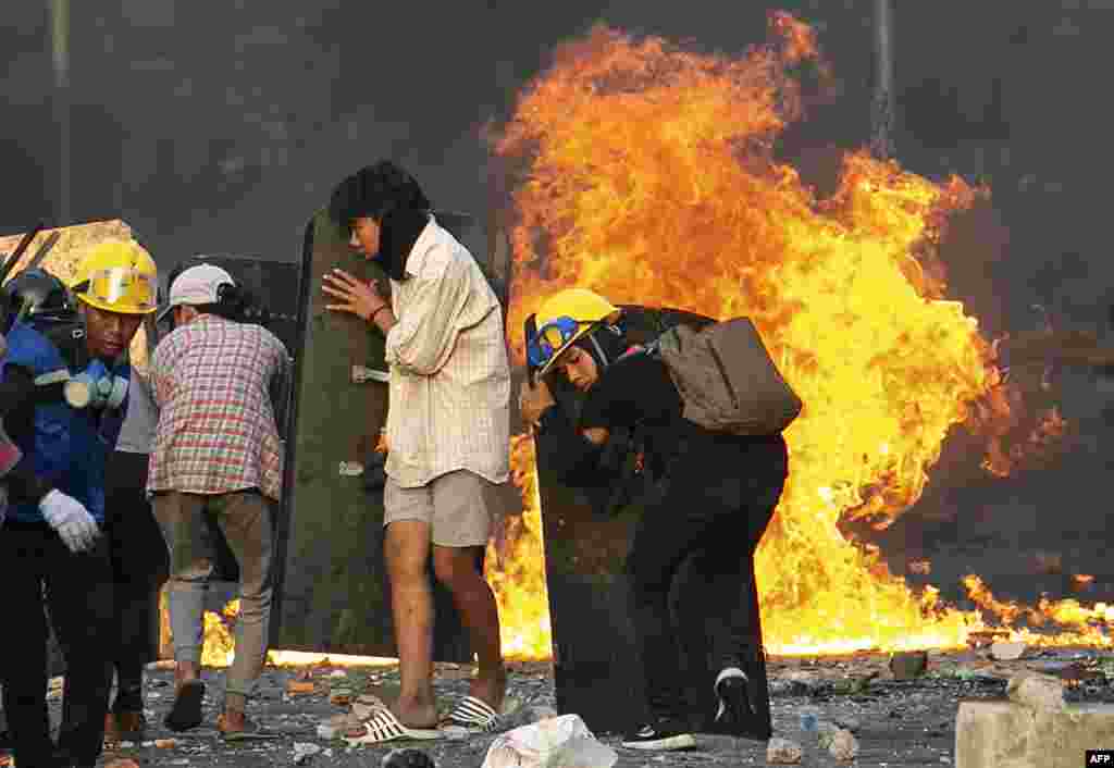 Protesters take cover behind homemade shields as they confront the police during a crackdown on demonstrations against the military coup in Yangon, Myanmar.
