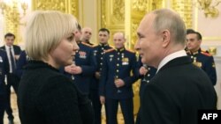 Президент Росії поруч з Марією Костюк, матір'ю російського солдата, якого посмертно нагородили орденом "Герой Росії". Цього дня, 8 грудня, Путін оголосив, що балотуватиметься на переобрання у 2024 р. Фото: Mikhail Klimentyev/Sputnik/Pool AFP