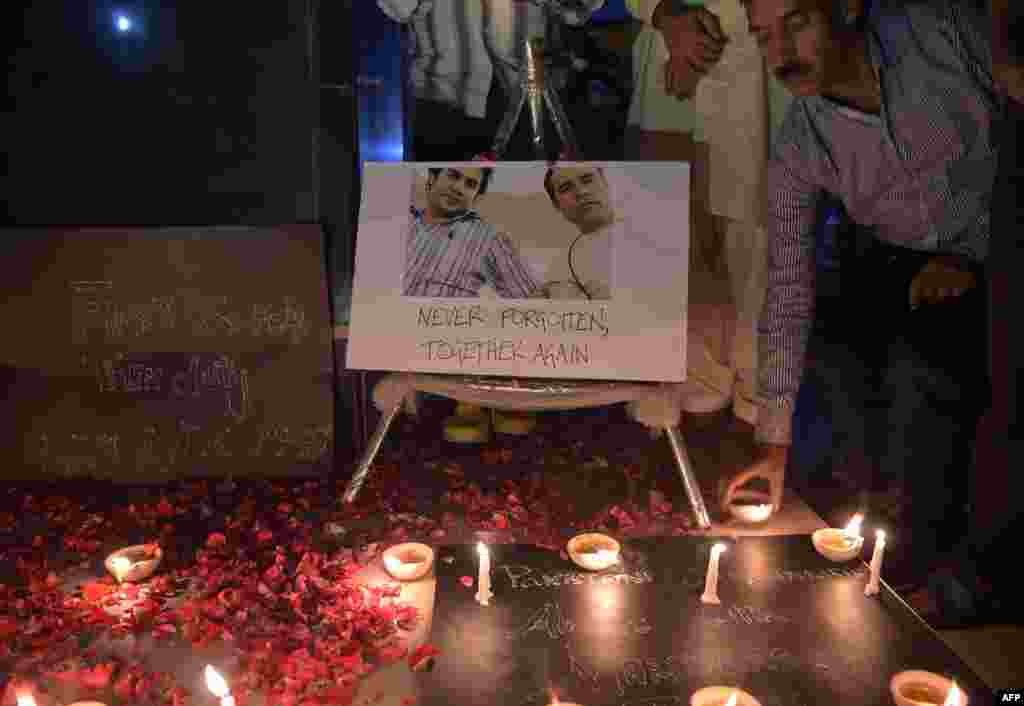 Pakistani journalists light candles and oil lamps next to a photograph of Agence France-Presse (AFP) chief photographer for Afghanistan Shah Marai, who was killed along with other Afghan journalists in a targeted suicide bombing, during a vigil in Islamabad.
