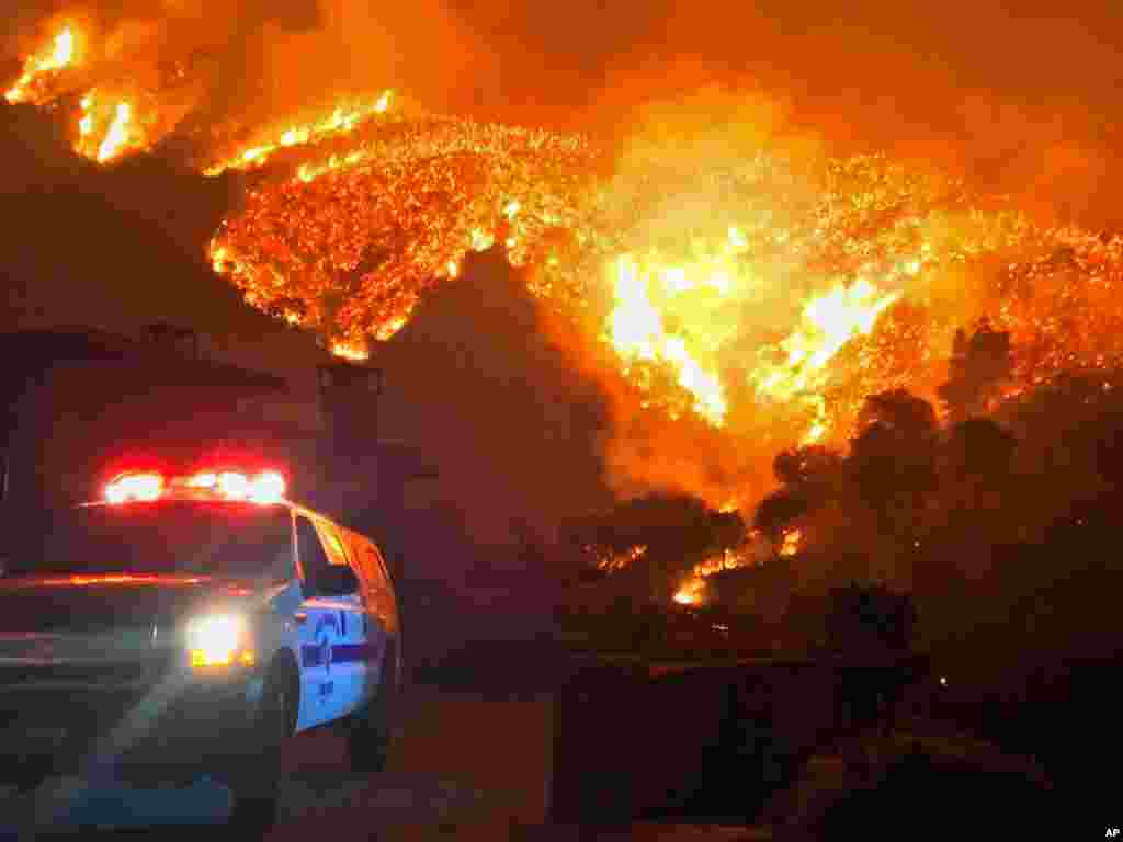 In this photo provided by the Santa Barbara County Fire Department, fire burns canyons and ridges above Bella Vista Drive near Romero Canyon as the fight to contain a wildfire continues in Montecito, California, Dec. 12, 2017.