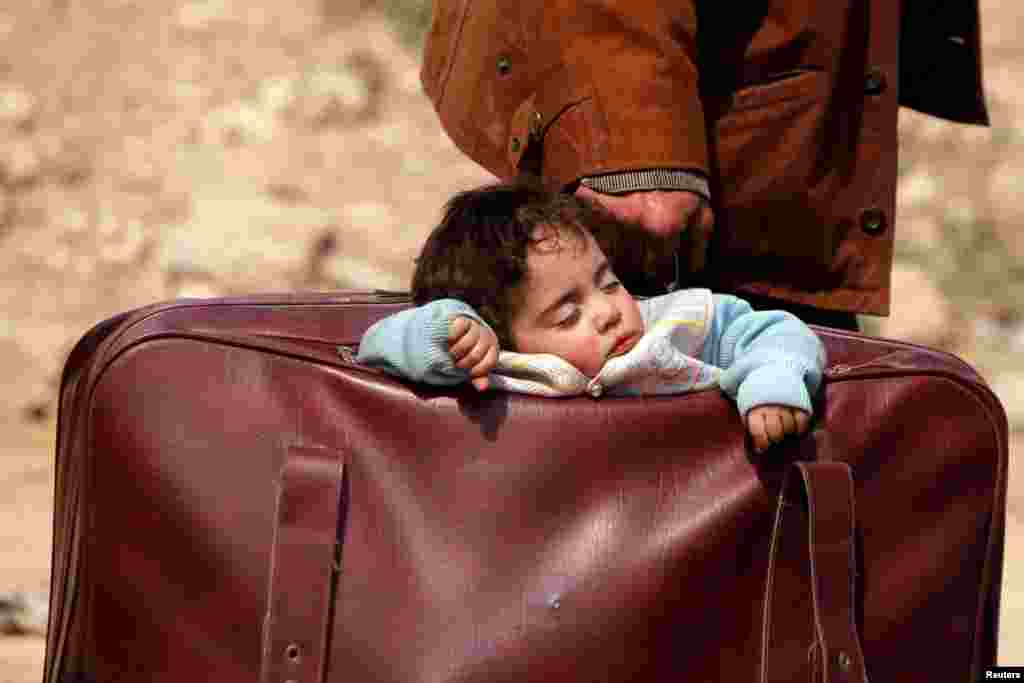 A child sleeps in a bag in the village of Beit Sawa, eastern Ghouta, Syria.
