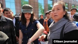 武汉市一位汪姓女青年在手铐打开一只后戴着手铐跟围观路人在一起。她被誉为学雷锋的女孩，2013年为救人助人，向执勤民警求助无果后，因用脚踢警车来宣泄愤怒而遭警察以手铐铐住（网络图片）