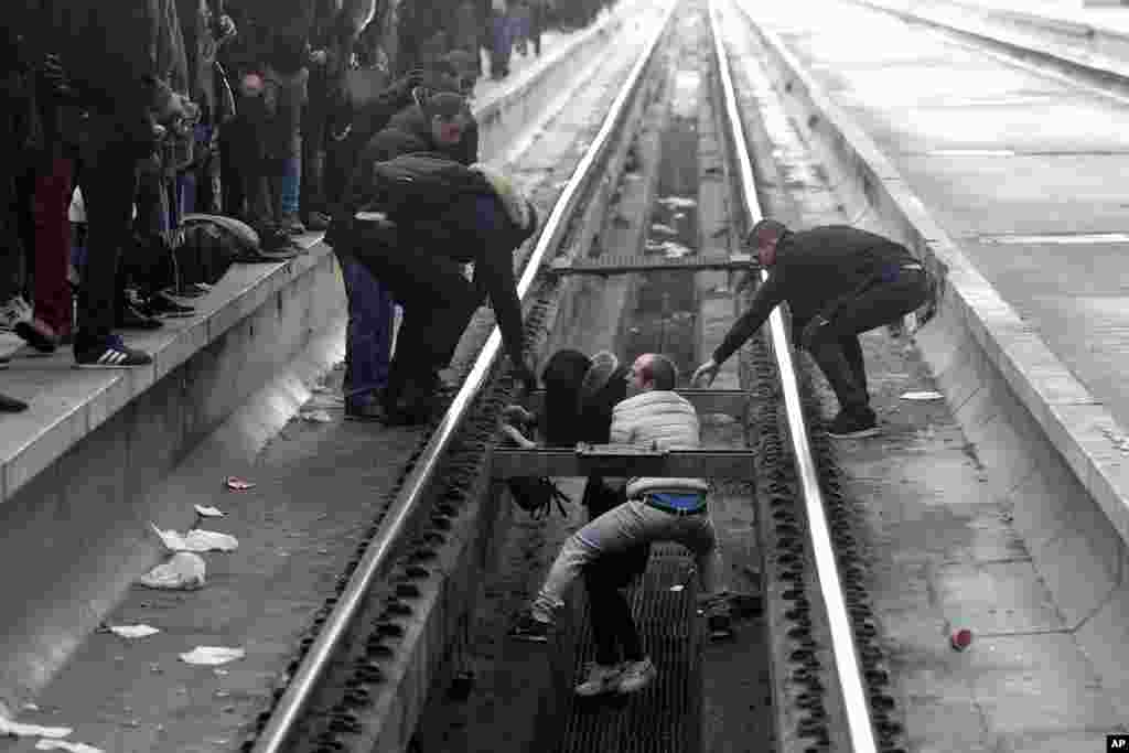 Passengers assist a woman who fell off a platform as she was trying to cross railroad tracks at Gare de Lyon train station, in Paris, as unions stage a mass strike.