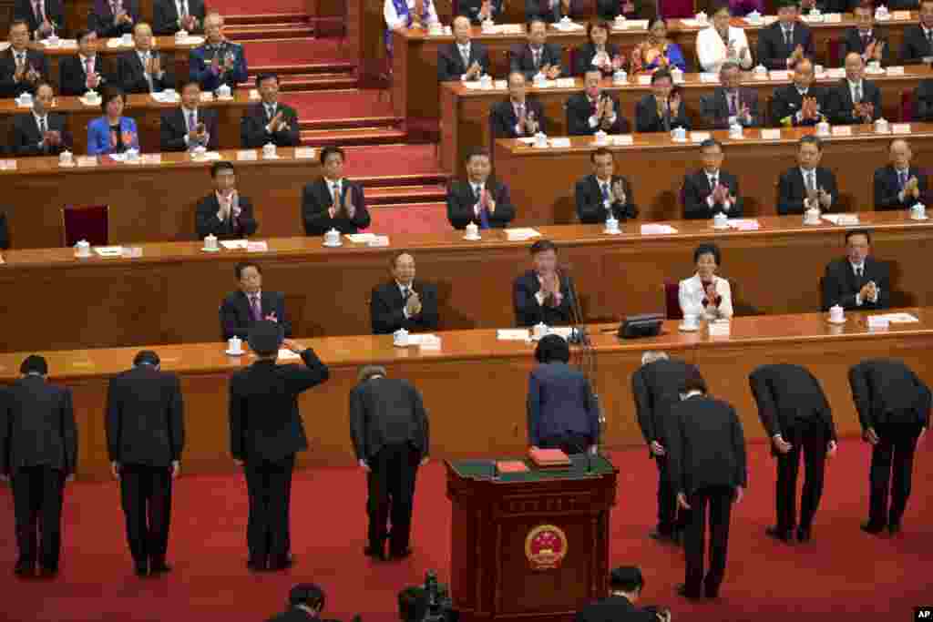 2018年3月19日在北京人民大会堂举行的中国全国人大全体会议上,新官员宣誓就职后,向人大主席团成员鞠躬,军人敬军礼。从图片上看背影,这些新官员似乎是中国副总理和国务委员,其中有女副总理孙春兰和国务委员、国防部长魏凤和。