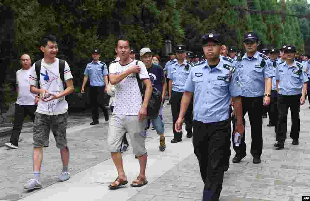 中国P2P网络理财民间集资受害者在北京被警察和保安人员带出公园,送上大巴拉走(2018年8月6日)。受害者从中国各地到北京请愿维权。当局出动上千警力和上百大巴,严阵以待。