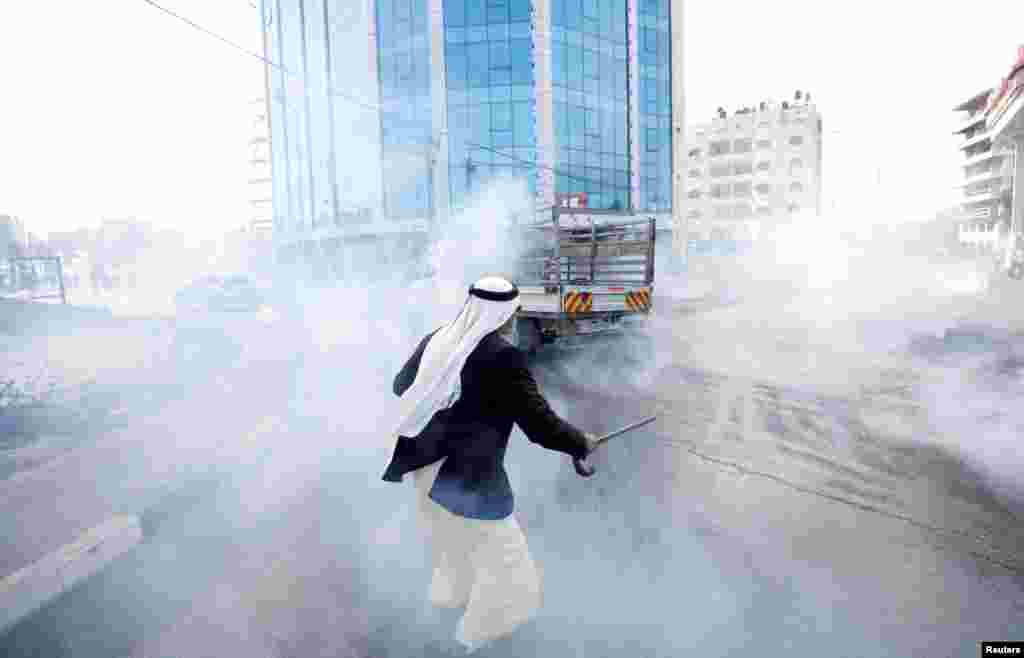 A Palestinian runs from tear gas fired by Israeli troops during clashes at a protest against U.S. President Donald Trump's decision on Jerusalem, near Ramallah, in the occupied West Bank.