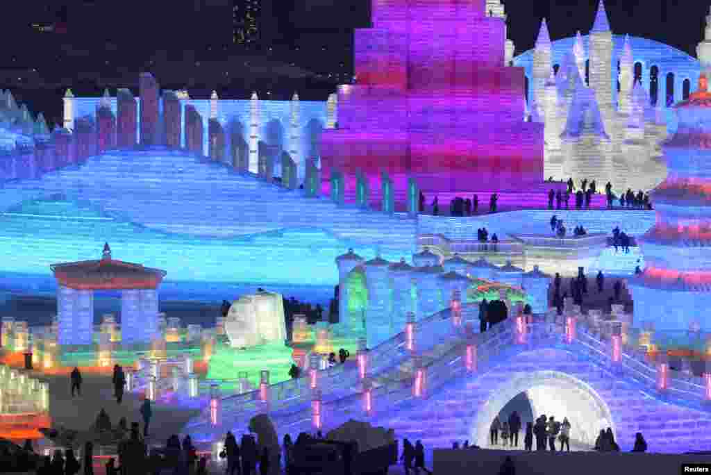在中国东北黑龙江省的哈尔滨国际冰雪节期间，游客观赏彩色灯光辉映着塔楼建筑冰雕（2019年1月4日）。冰雪节是哈尔滨一项大型冰雪旅游项目。一些游客提前来到哈尔滨，感受冰雪世界的美景。有些游客来自常年温暖的中国南方地区。
