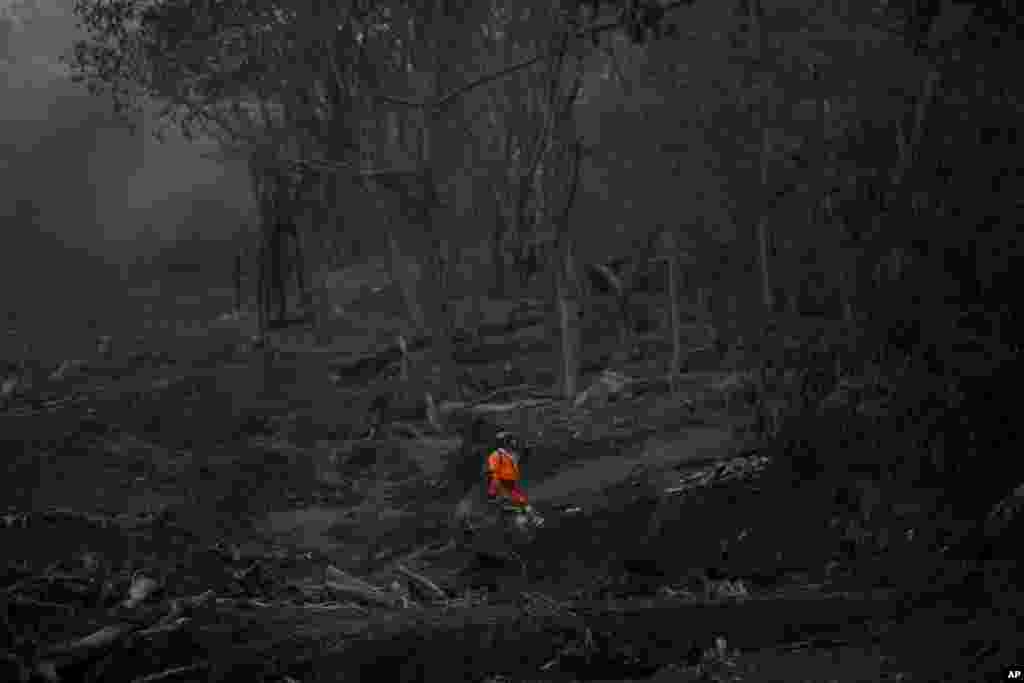 A rescuer looks for bodies in the area close to where the Las Lajas bridge used to be, after the eruption of the Volcan de Fuego, or Volcano of Fire, in El Rodeo, Guatemala.