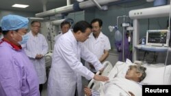 中国总理李克强在湖北省监利县一家医院与一位受伤的女乘客交谈。