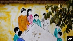 资料照片: 新疆和田团结新村一所住宅内显示维吾尔和汉族男女共持五星旗的壁画。(2018年9月20日)