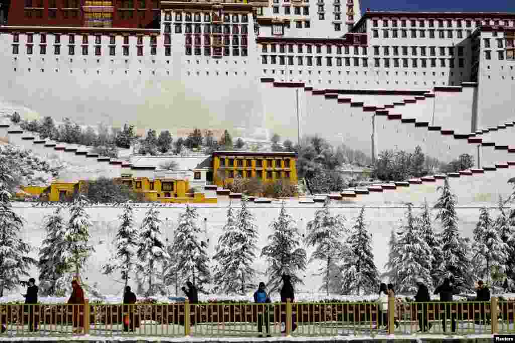 2018年12月19日,中国西藏自治区拉萨布达拉宫外,人们走过白雪覆盖的树木。被中国当局视为敏感地区的西藏自治区的官方2019年1月10日宣布,将在今年完善境外游客进藏旅游管理办法,争取将进藏审批时间缩短一半、境外游客人数增加五成。此前,美国去年12月19日通过的《西藏旅行对等法》法案旨在反击中国严格限制包括美国人在内的外国人进入西藏。法案要求中国政府必须允许美国记者、外交官和游客不受限制地前往西藏;美国国务卿必须每年向国会递交报告,指证涉及相关限制政策的中国官员,这些官员将被限制进入美国。目前中国的外交官、记者、游客等能在美国各地自由旅行,但是中国当局长期以来一直限制美国公民访问或享有进入西藏的同等权利。根据外交对等原则,国与国之间应向对方公民提供对等的权利。