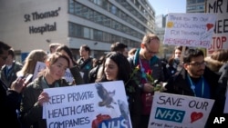 Madaktari wa ngazi ya chini wakiwa wameshikilia mabango wakishiriki katika kuanza kwa mgomo nje ya Hospitali ya St Thomas' jijini London, Jumanne, Aprili 26, 2016.
