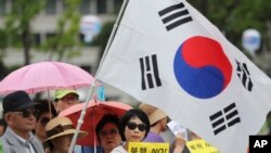 韩国民众手举标语牌和国旗集会支持在韩国部署萨德导弹防御系统（2016年7月18日）