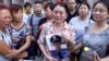 In this image taken from a video footage from AP Video, a woman holds up a photo of her son, a missing firefighter, outside a hotel where officials held a daily media conferences in northeastern China's Tianjin municipality, Aug. 16, 2015.