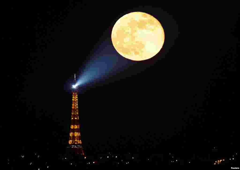 The full moon, known as the "Super Pink Moon" rises behind the Eiffel Tower in Paris, France, April 27, 2021.
