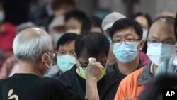 资料图片：2022年11月26日星期六，在台湾新北市一投票站，当地居民在投票前被检查体温。周六，台湾各地选民前往投票站参加备受关注的地方选举。在2024年总统选举之前，这次选举将决定台湾主要政党的实力。（美联社）