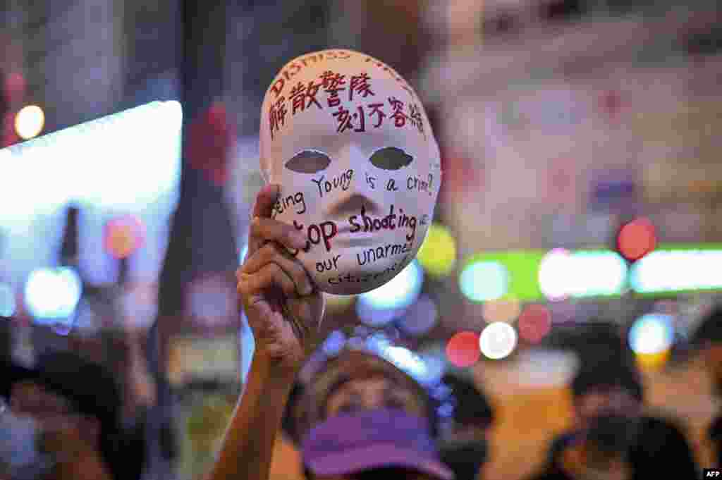 在香港旺角警局外,一名女子手持写着"解散警队 刻不容缓“的面具参加示威活动 (2019年10月5日)