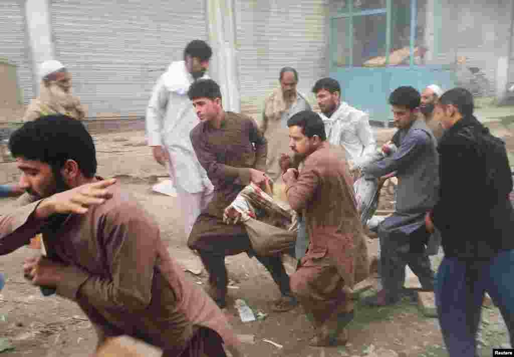 Afghan men carry an injured man after a blast in Jalalabad.
