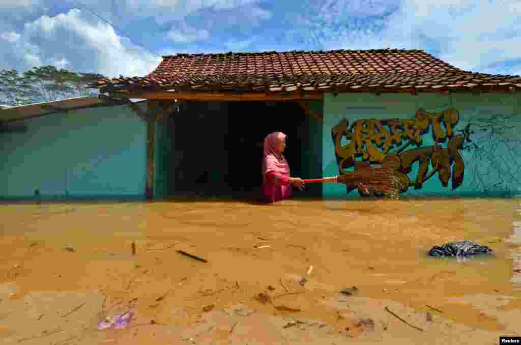 A woman villager cleans garbage in front of her house as flood hits Tanjungsari village in Tasikmalaya, Indonesia.