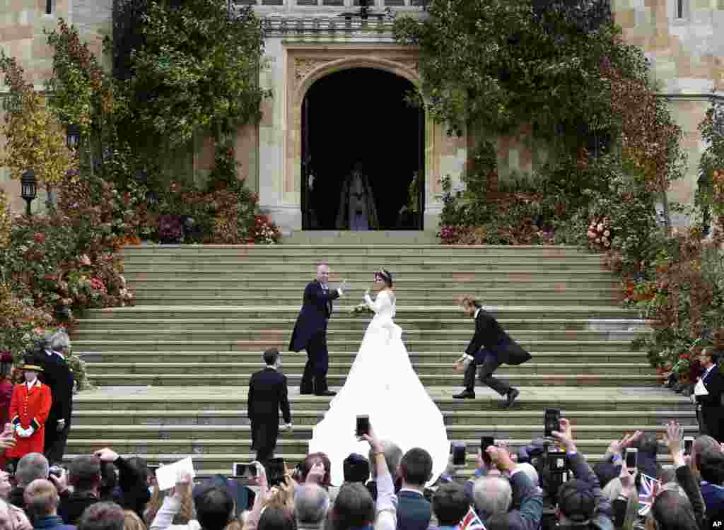 英国约克公主尤金妮2018年10月12日在父亲安德鲁王子的陪同下抵达英国伦敦附近的温莎城堡参加婚礼。