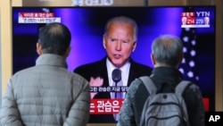 行人在韩国首尔火车站的电视屏幕前观看胜选美国总统的拜登讲话。（2020年11月8日）