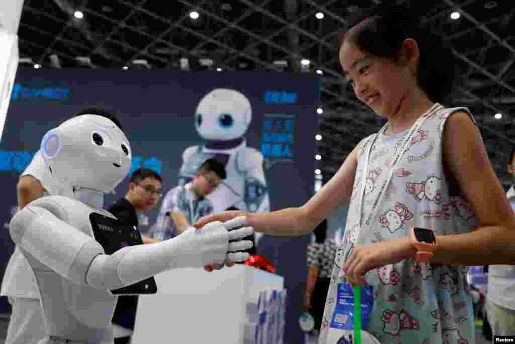 2018年7月4日,上海2018中国国际机器人展览会上,一位访客与机器人握手。
