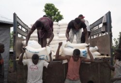 FILE - Volunteers unload maize meal supplied by the United Nations Food Program at the Lovua refugee camp in Angola, Sept. 13, 2017.