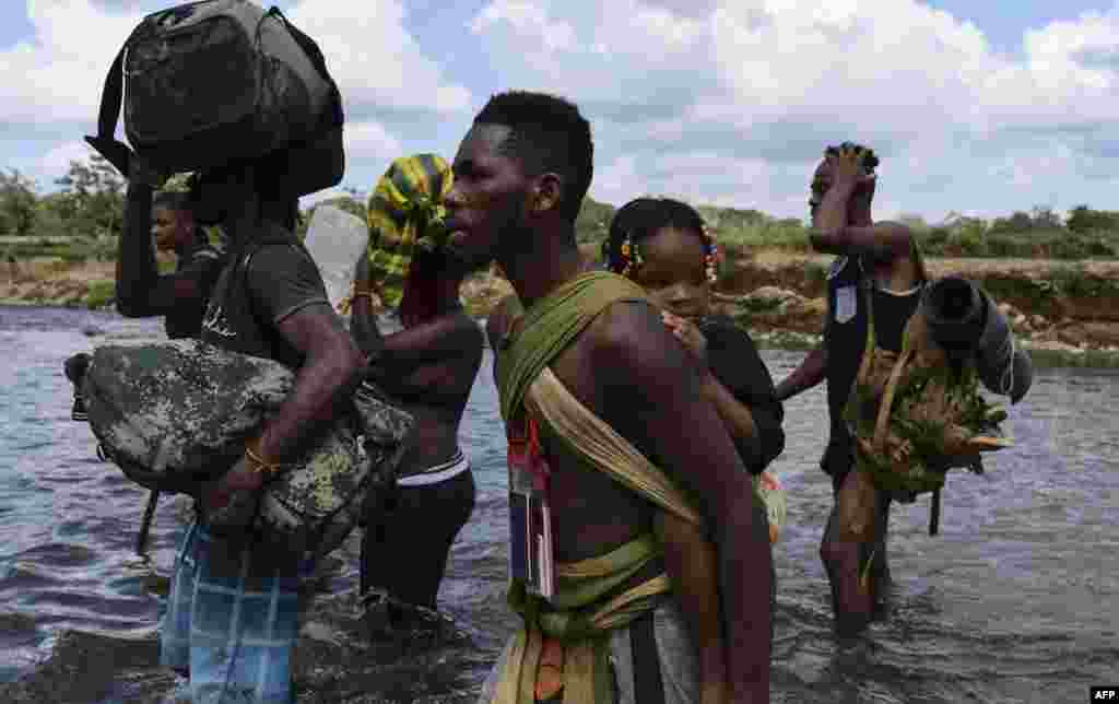 Migrants cross the Chucunaque river after walking for five days in the Darien Gap, in Bajo Chiquito village, Darien province, Panama, Feb. 10, 2021, on their way to the U.S.