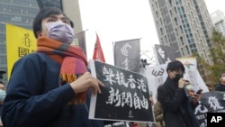资料照片：一名抗议人士举着“声援香港新闻自由”的标语牌站在中国银行位于台北的分行外。(2021年12月30日)