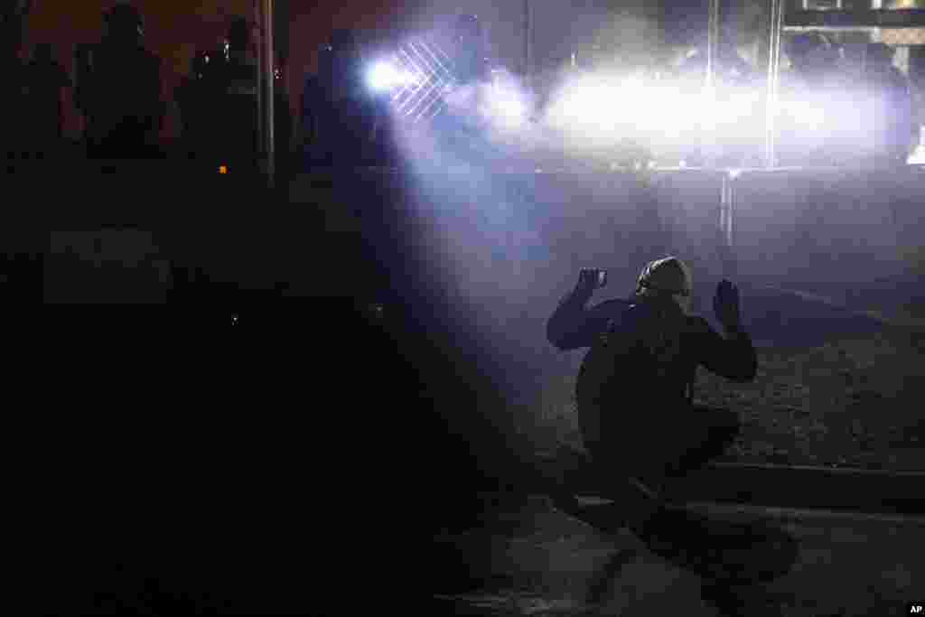 Police shine lights on demonstrator with raised hands during a protest over Sunday's fatal shooting of Daunte Wright during a traffic stop, outside the Brooklyn Center Police Department in Brooklyn Center, Minnesota.