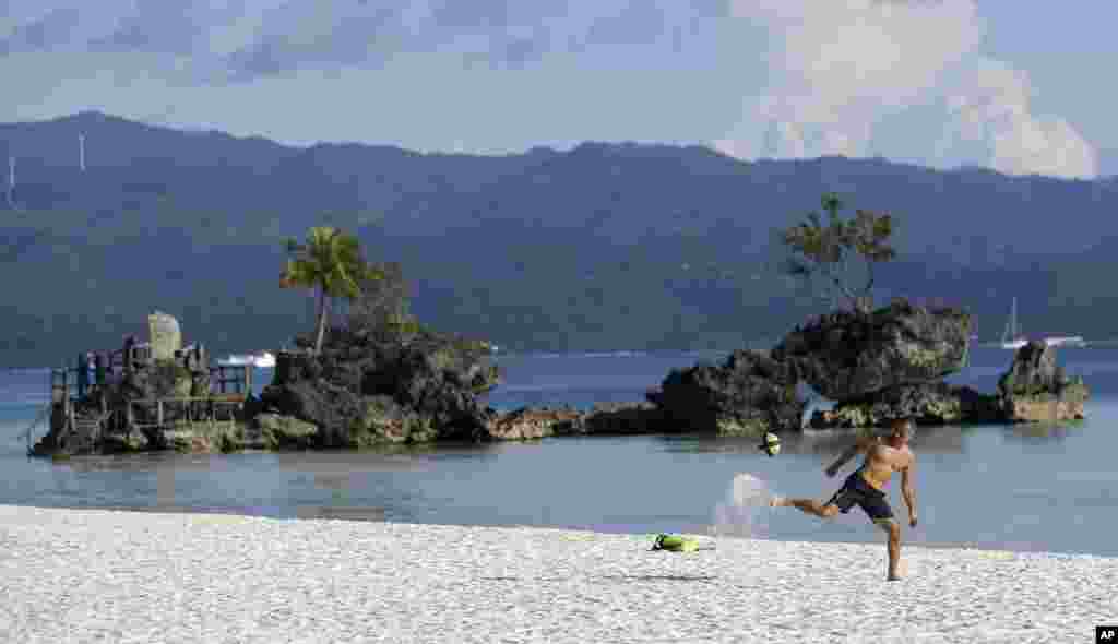 A foreign tourist plays football, as the government implements the temporary closure of the country's most famous beach resort island of Boracay, in central Aklan province, Philippines.