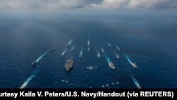 资料照:美国尼米兹级核动力航母“罗纳德·里根号”,日本海上自卫队“日向号”直升机驱逐舰,以及美日其他16艘战舰在菲律宾海进行演习。(2018年11月8日)