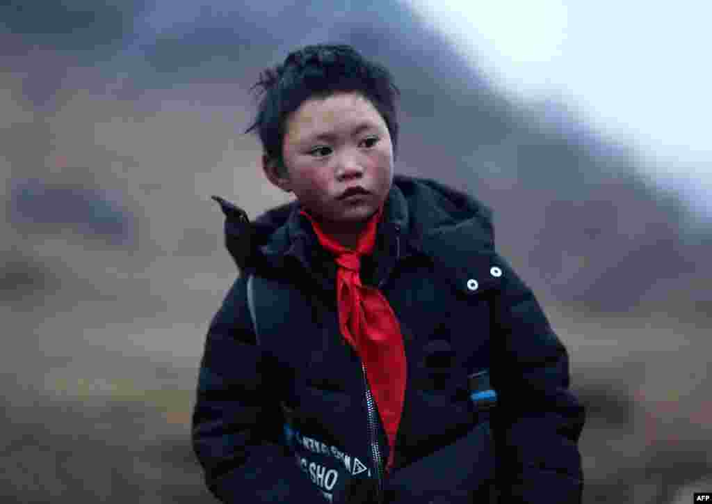 云南山区鲁甸的8岁小学生王福满(2018年1月11日)。王福满身穿单薄衣服攀爬山路走到学校,头发上结满了白冰花的“冰花男孩”照片广泛流传。