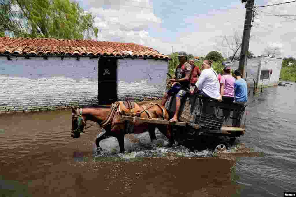 People ride on a horse carriage through a flooded street after heavy rains caused the river Paraguay to overflow, in Asuncion, Paraguay, Jan. 22, 2018.