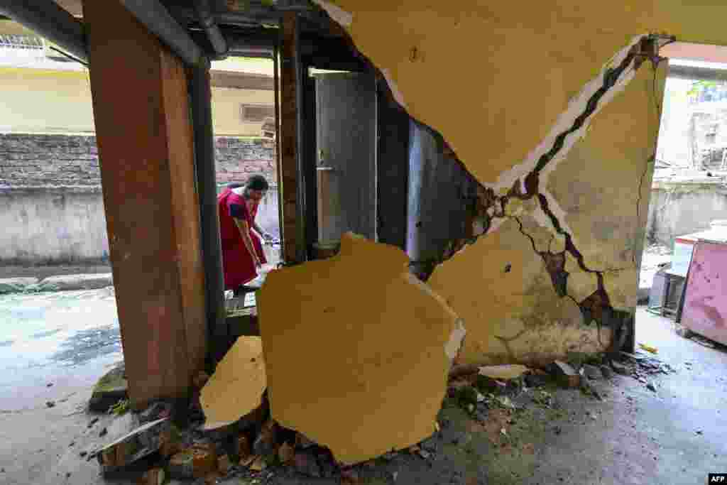 A woman collects water from a tap near a collapsed wall at an apartment building in Guwahati after a strong earthquake hit Assam in northeastern India, damaging buildings. There were no immediate reports of casualties.