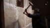 FILE - This image made from video posted on a militant social media account affiliated with the Islamic State group, April 11, 2015, purports to show a militant taking a sledgehammer to an Assyrian relief at the site of the ancient Assyrian city of Nimrud, which dates to the 13th century B.C.