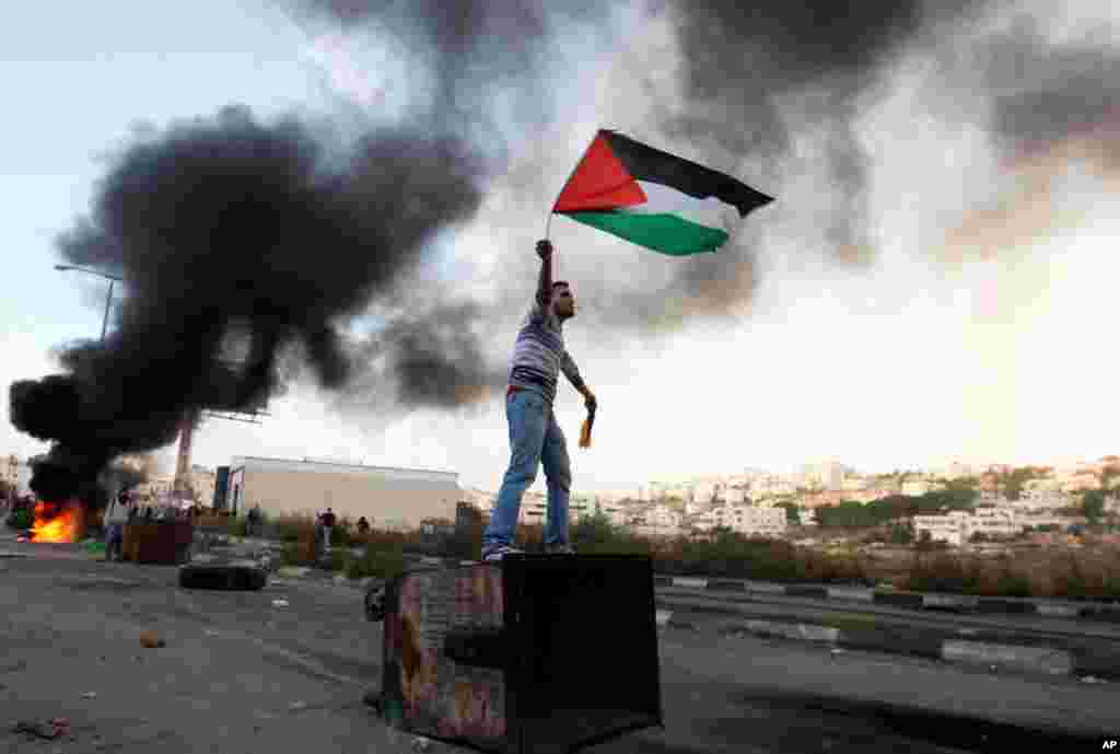 Một người đàn ông Palestine vẫy cờ trong cuộc biểu tình chống lại chiến dịch quân sự của Israel ở Dải Gaza, ngày 18/11/2012. .