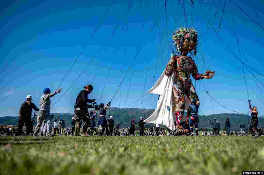 Performers and staff control the giant puppet 'MOCCO' designed by Noriyuki Sawa during the "Rediscover Tohoku - MOCCO's Journey from Tohoku to Tokyo" media tour at Takata Matsubara Tsunami Reconstruction Memorial Park in Rikuzentakata, Iwate Prefecture, Japan, May 15, 2021. 