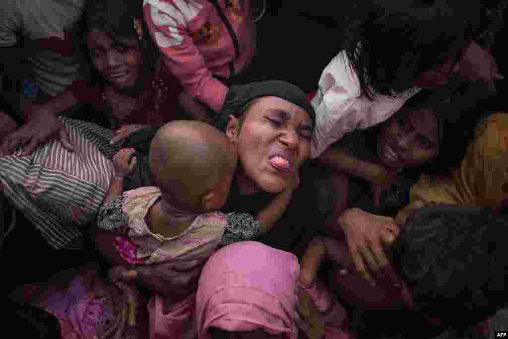 Rohingya Muslim refugees react as police and officials attempt to control a surging crowd as they wait to be called to receive food aid of rice, water, and cooking oil in a relief center at the Kutupalong refugee camp in Cox's Bazar, Bangladesh.